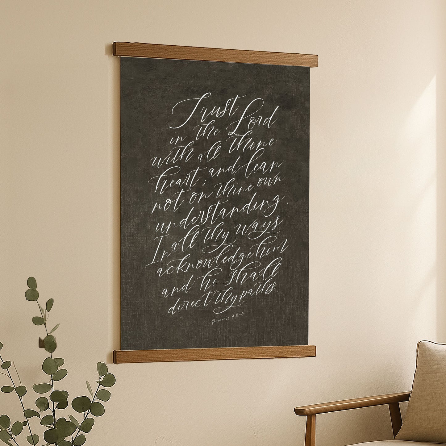 a blackboard with white handwritten text, hanging on a wall next to a plant.