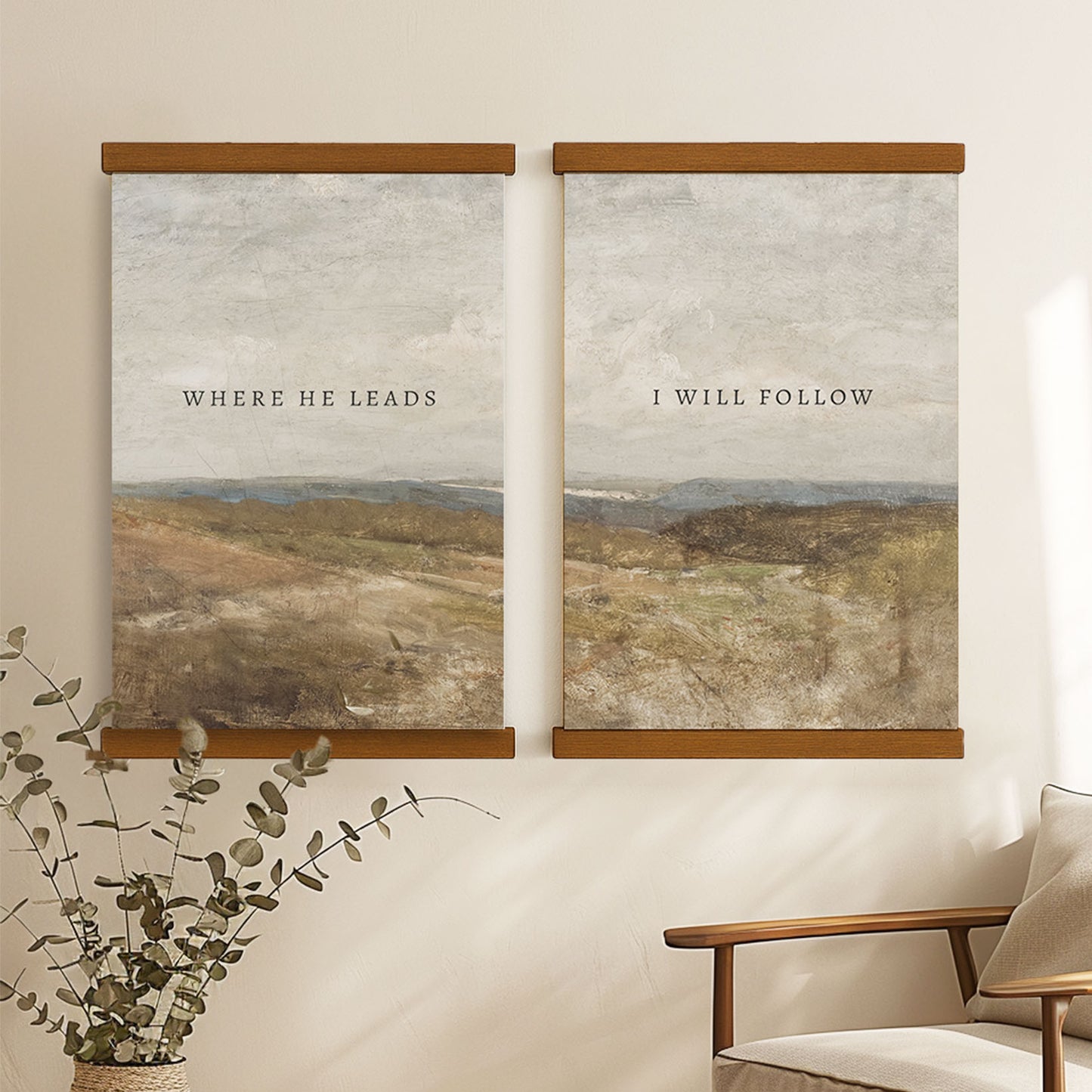 two framed paintings hanging on a wall, each depicting a landscape scene. The text on the paintings reads "WHERE HE LEADS" and "I WILL FOLLOW".