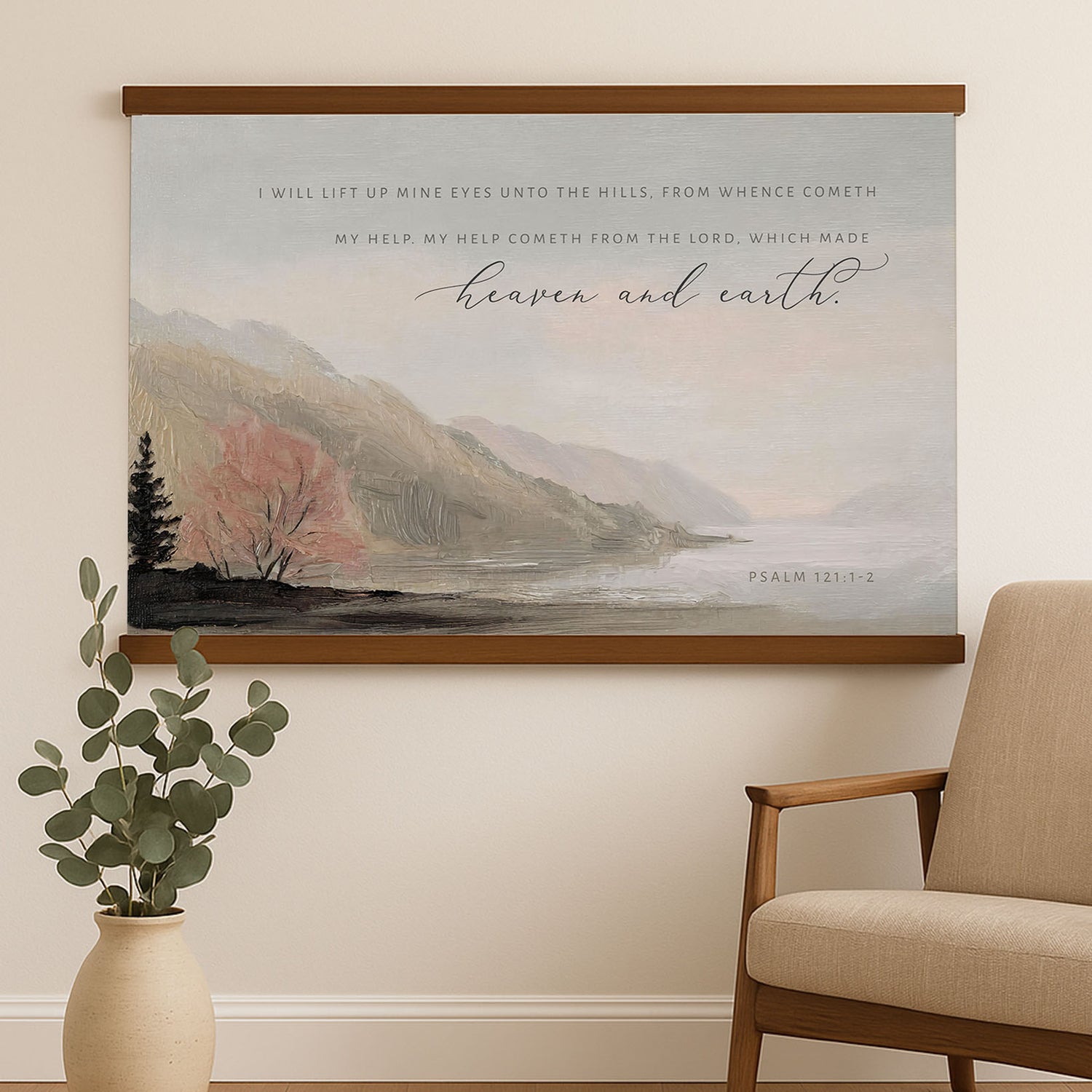 a large canvas print of a serene landscape with mountains, trees, and a body of water, hanging on a wall above a wooden chair.