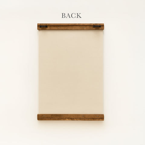 a wooden frame with a blank canvas or paper inside, mounted on a white wall.