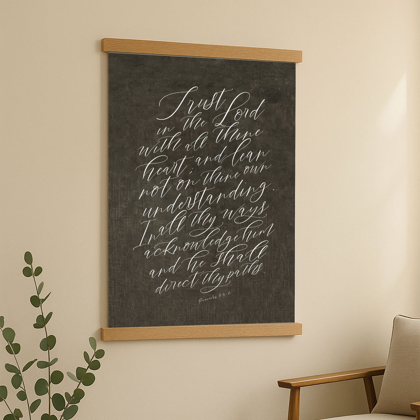 a blackboard with white handwritten text, hanging on a wall next to a plant.