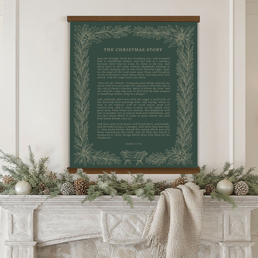 a fireplace mantel decorated with pine cones, ornaments, and a white blanket draped over it. Above the mantel hangs a framed poster with a Christmas-themed design and text.
