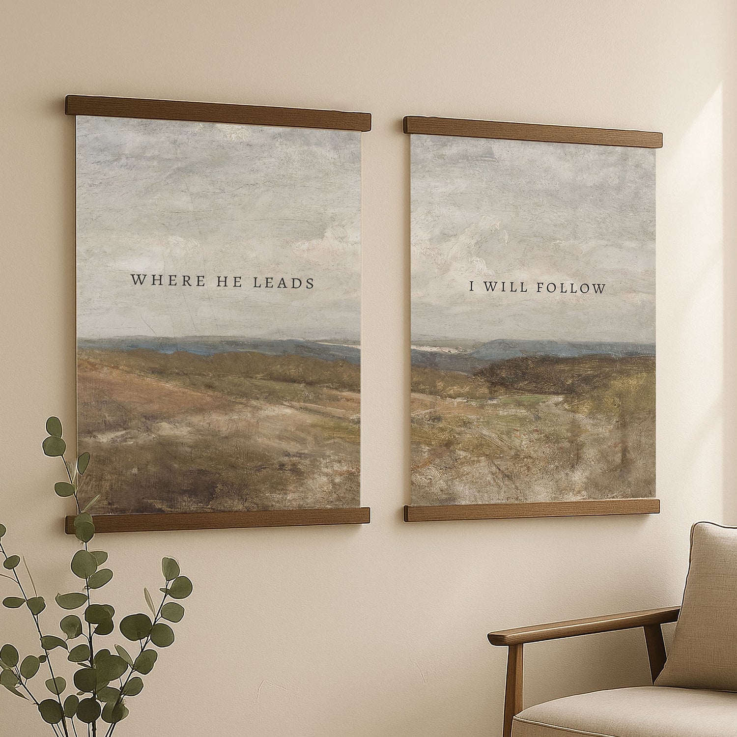 two framed paintings hanging on a wall, each depicting a landscape scene. The text on the paintings reads "WHERE HE LEADS" and "I WILL FOLLOW", respectively.