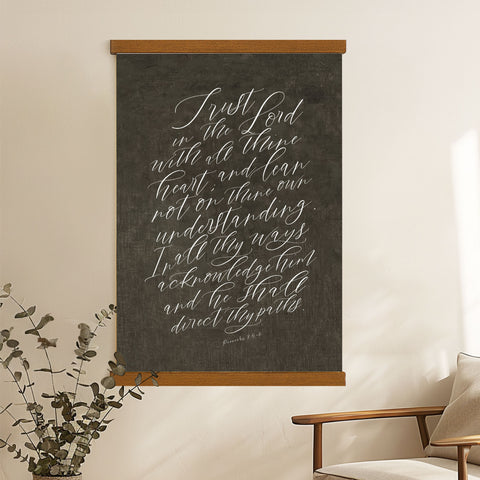 a blackboard with white handwritten text, hanging on a wall next to a wooden chair.