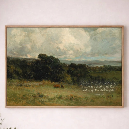 a painting of a pastoral landscape with a cow grazing in the foreground, hanging on a white wall above a wooden table with a plant on it.