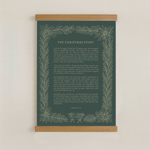 The image is a framed print of a Christmas-themed text, with a dark green background and a decorative border of leaves and flowers.