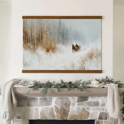 A framed painting of a horse-drawn sleigh in a snowy forest hangs above a stone fireplace mantle decorated with pine branches and pinecones.