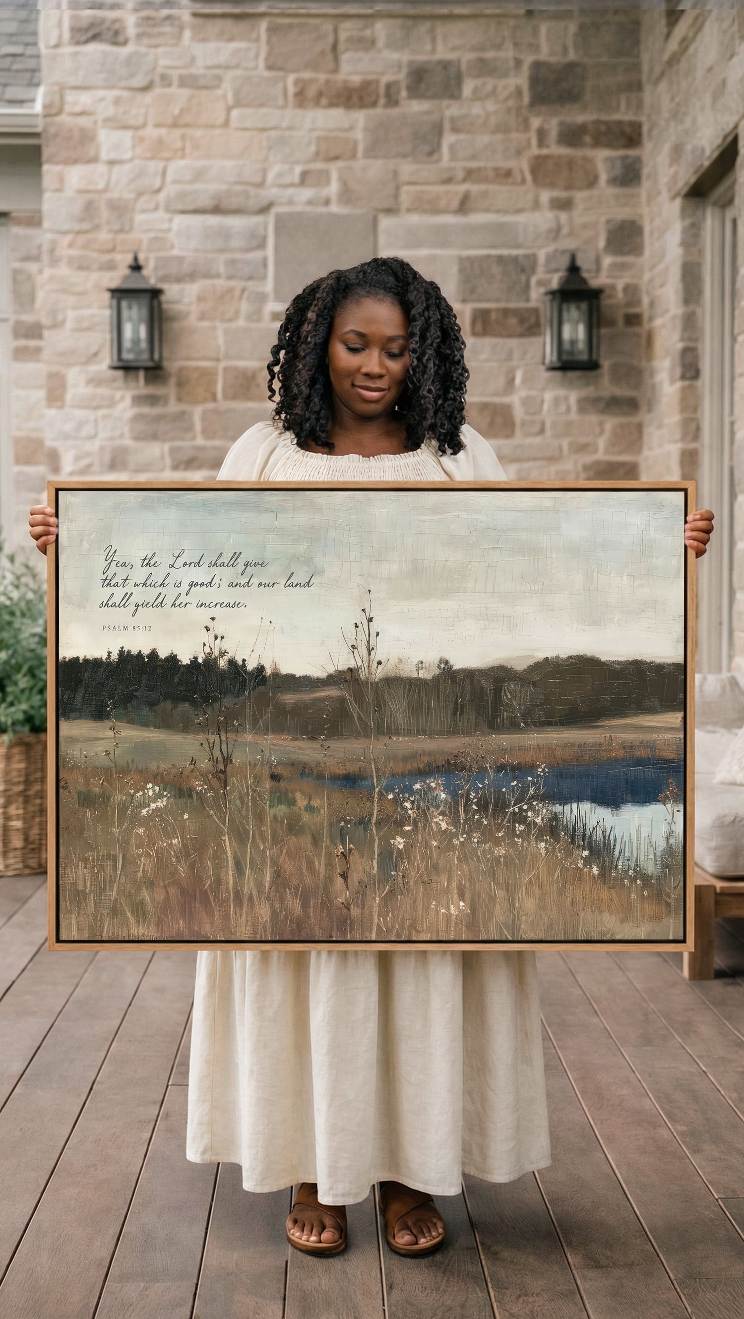 A woman in a white dress holds a large painting of a serene landscape, including a field and a body of water, with a text overlay that reads "From the Lord shall you have enough land, so you shall yield your land to the Lord."
