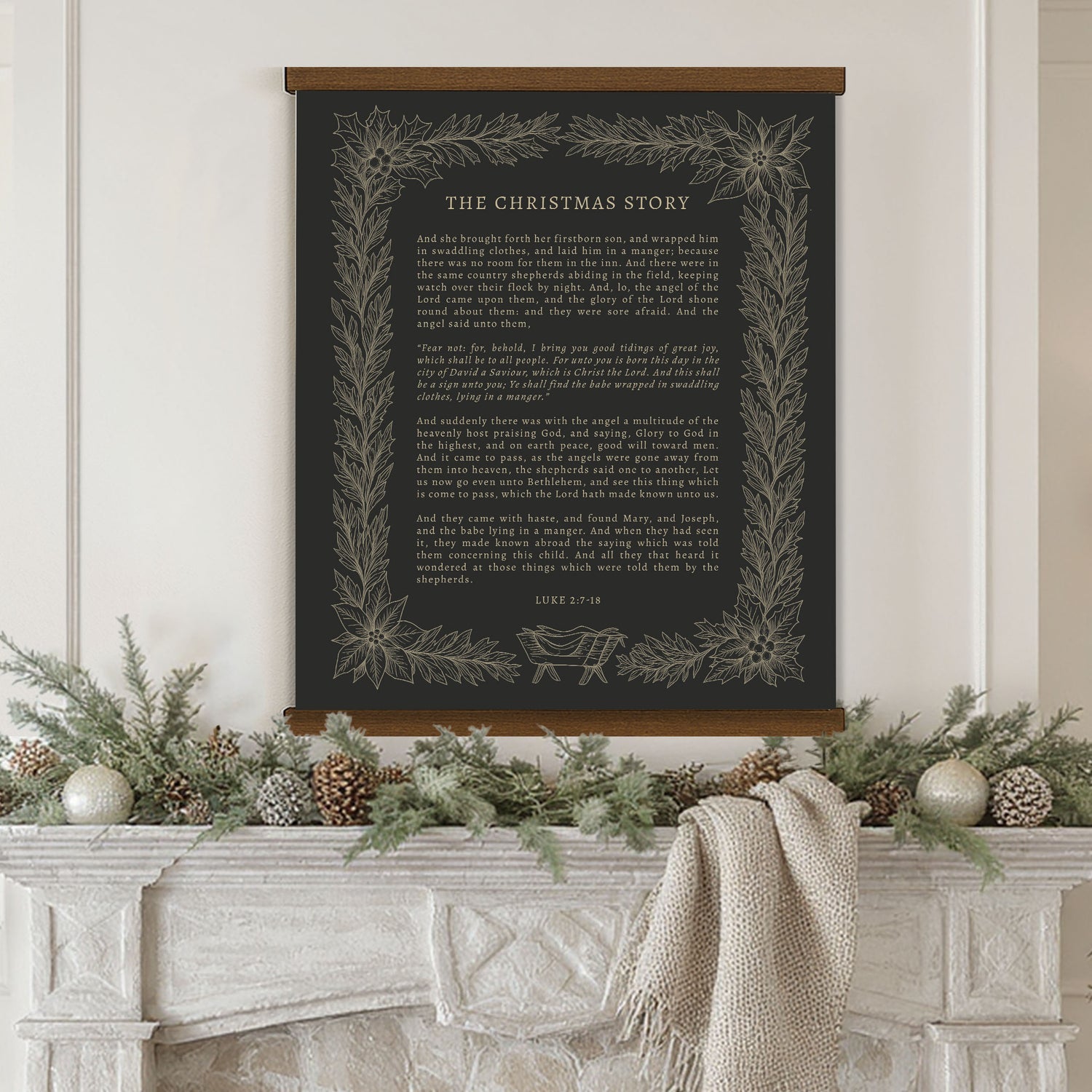 a black framed poster with a Christmas-themed text, hanging above a fireplace decorated with pine cones, greenery, and ornaments.