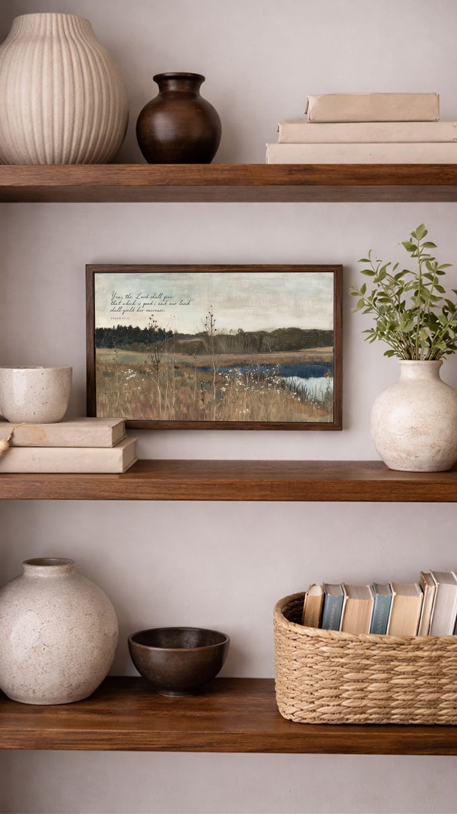 a wooden bookshelf with various decorative items and books arranged on the shelves. The bookshelf has three shelves, and the items include a painting, a vase, a bowl, and a basket. The painting depicts a serene landscape, and the vase and bowl are white, while the basket is brown. The books on the shelves are arranged in a way that they are easily accessible and add a touch of personalization to the space.