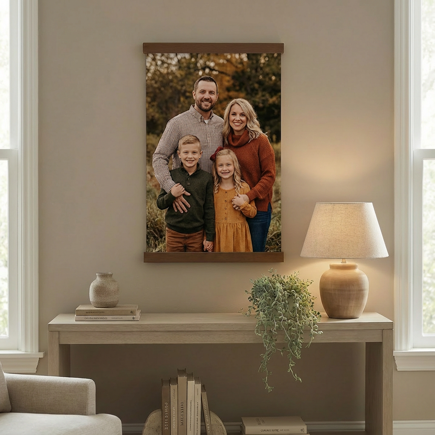 a family portrait hanging on a wall, with a table and lamp below it.