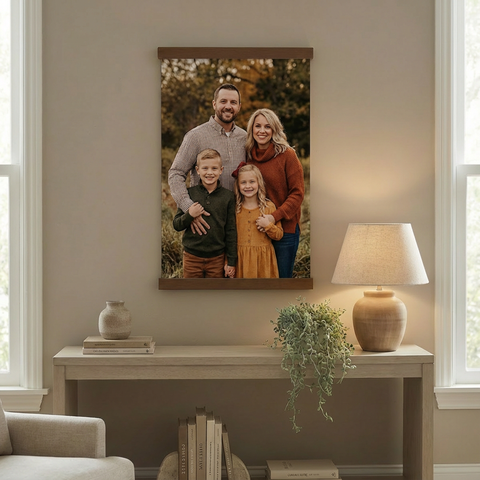 a family portrait hanging on a wall, with a table and lamp below it.