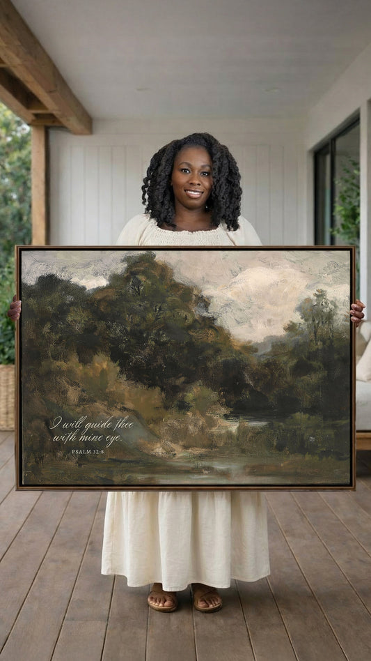 A woman in a white dress holds a large painting of a landscape with trees and a body of water.