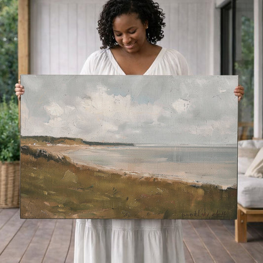 A woman in a white dress holds up a large painting depicting a serene landscape with a beach and ocean in the background.