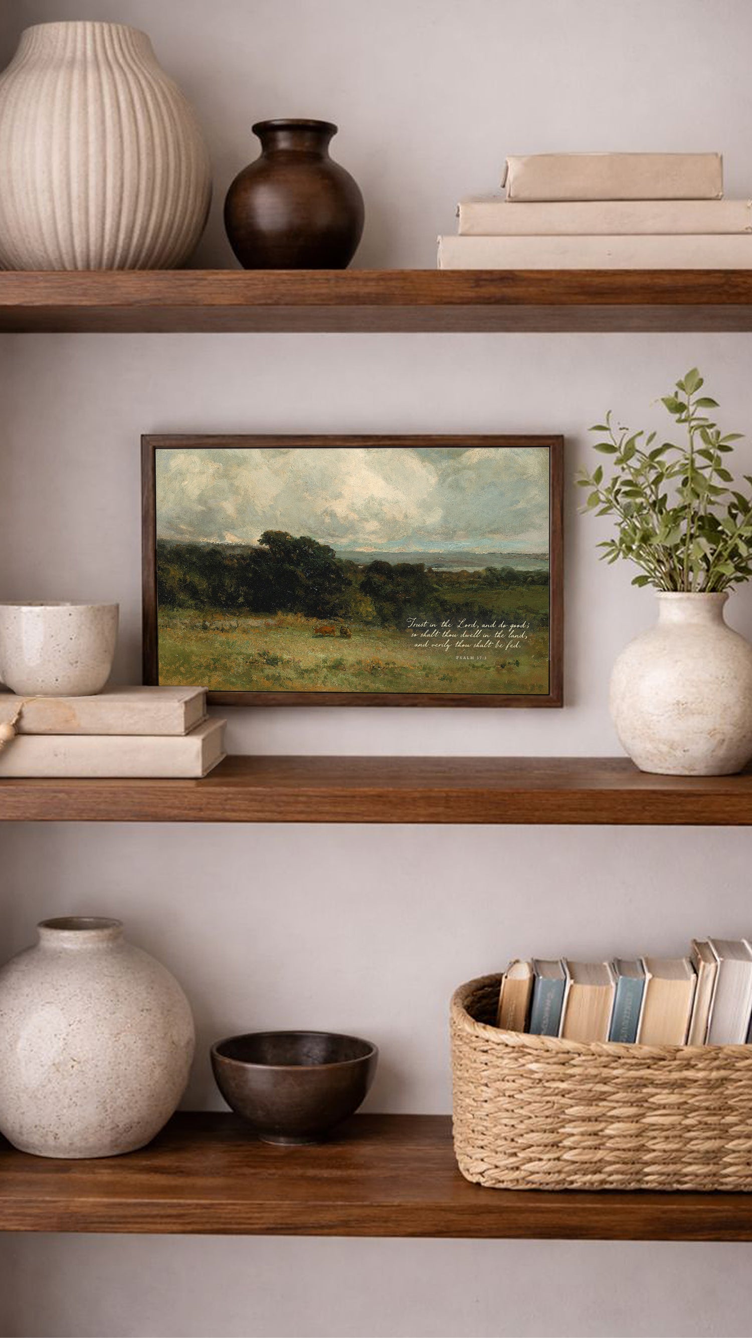 a wooden bookshelf with various decorative items and books arranged on the shelves. The bookshelf has three shelves, and there are several vases, bowls, and a painting displayed on the shelves. The painting is a landscape painting depicting a field with trees, and the bookshelf also contains several books and a basket.