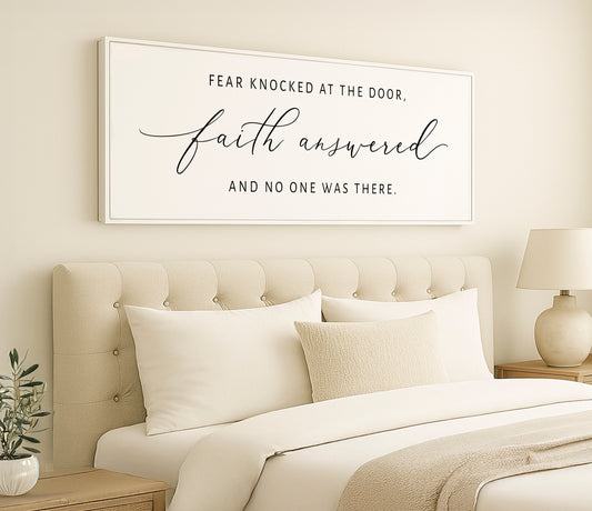 a bedroom with a white bed and a framed sign above it