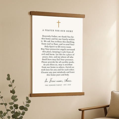 A framed prayer for our home with a cross and a plant in the background.
