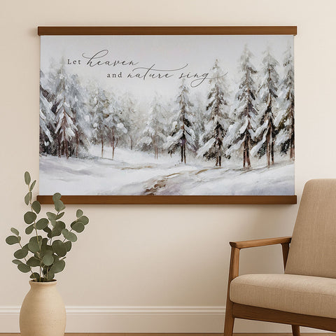 a large painting of a snowy forest scene hanging on a wall, with a potted plant to the left and a chair to the right.
