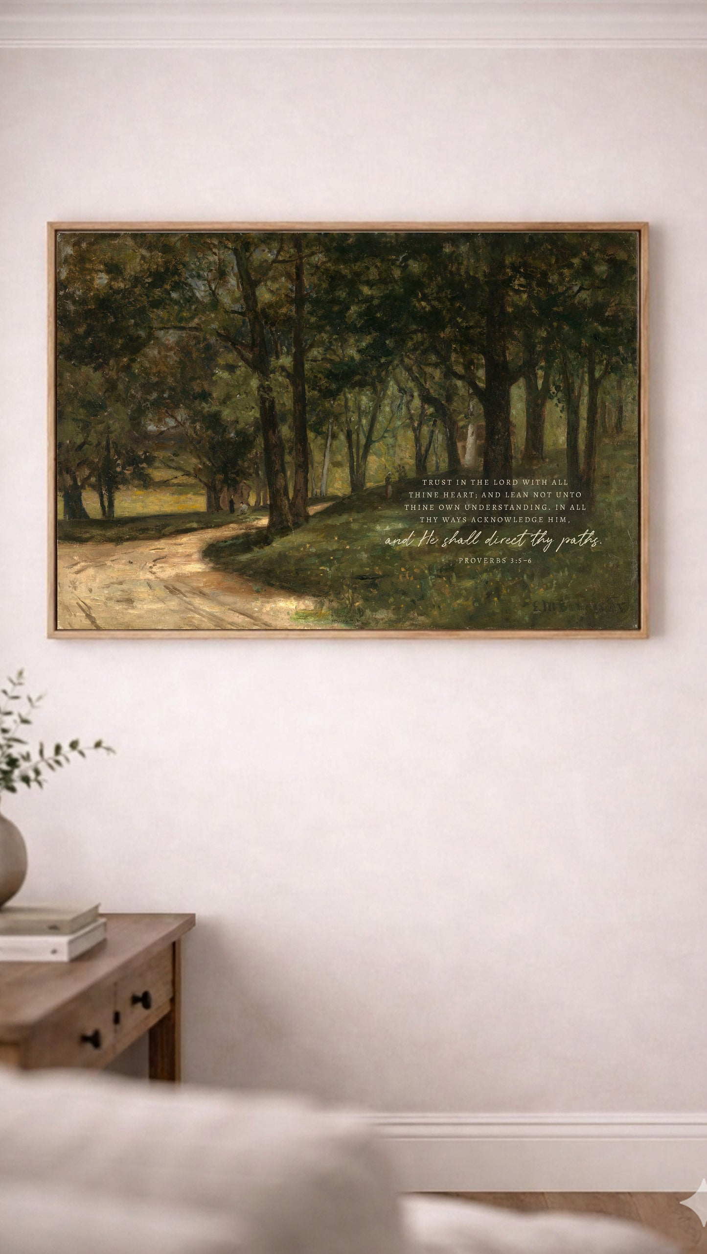 a painting of a forest scene hanging on a white wall, with a quote from the Bible visible below the painting.
