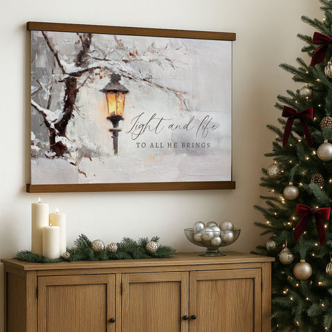 a wooden cabinet with a bowl of silver ornaments on top, a lit lantern, and a Christmas tree decorated with ornaments and lights.