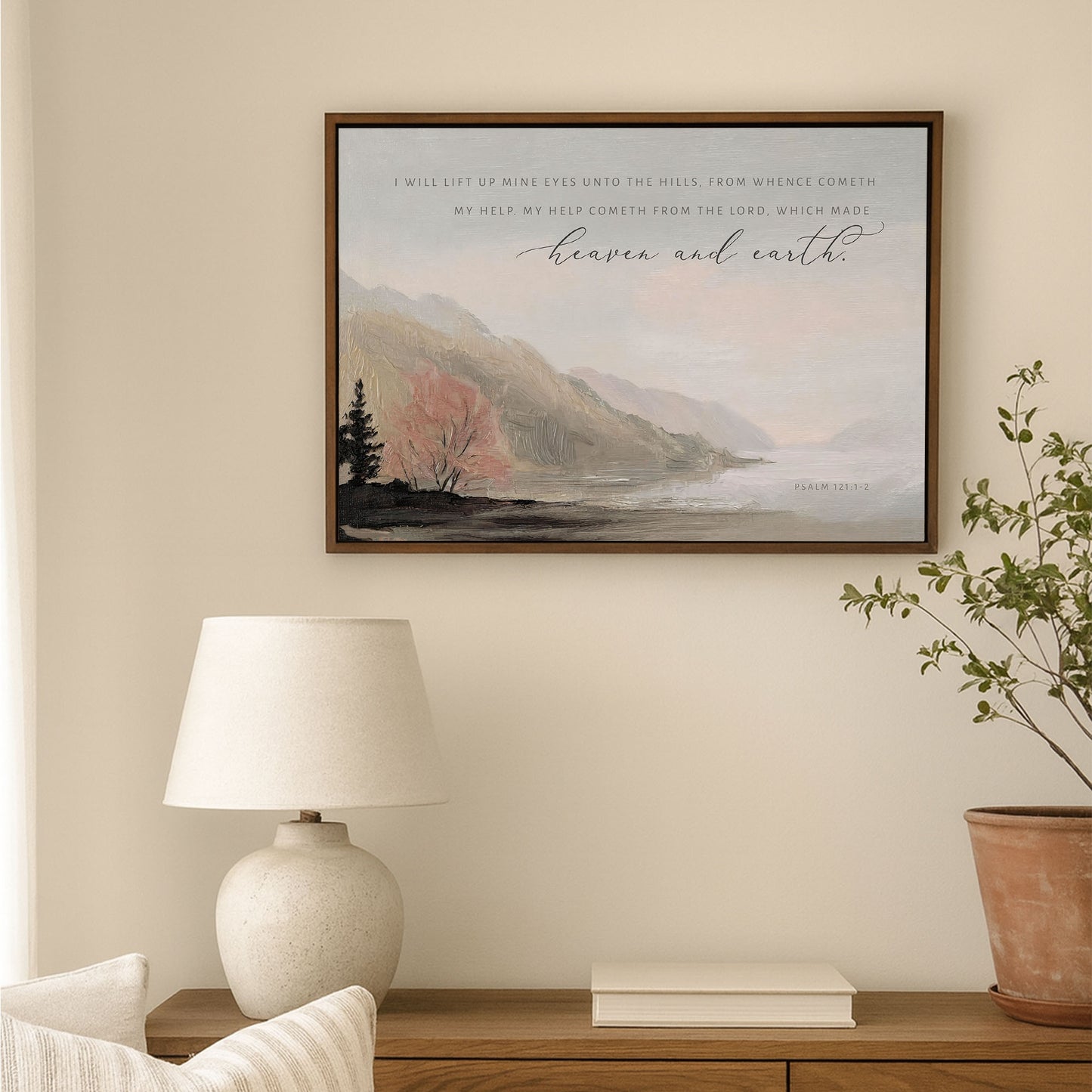 a serene indoor setting with a framed landscape painting hanging on the wall, a lamp on a wooden table, and a potted plant nearby.