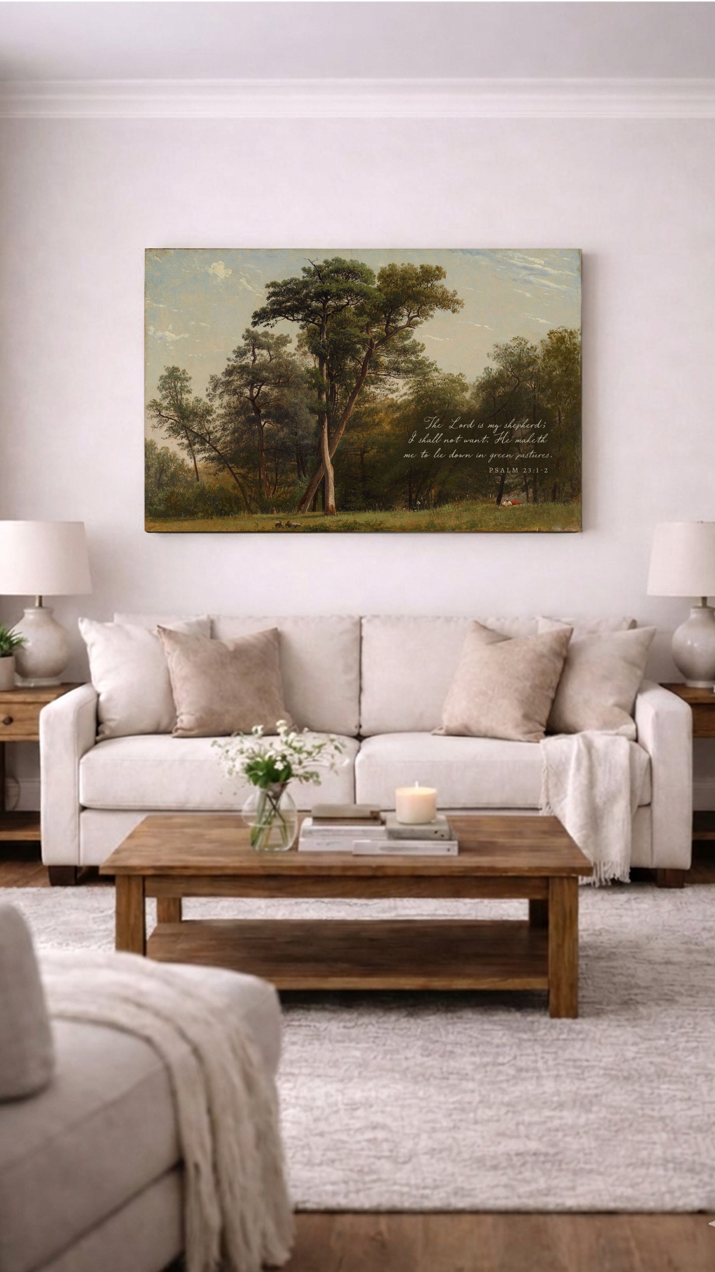 a living room with a large painting of a forest scene hanging on the wall above a beige sofa. The sofa is positioned in front of a wooden coffee table, which has a vase of flowers and a lit candle on it. The room also includes a rug and a side table with a lamp.