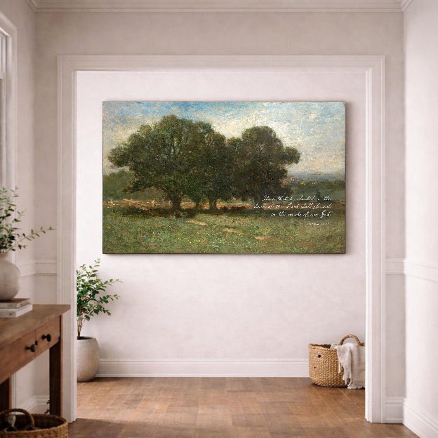 a large painting of a serene landscape with a group of trees in the foreground and a grassy field in the background. The painting is hung on a white wall in a room with a wooden floor.