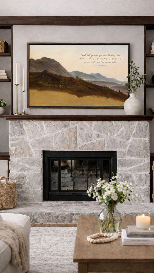 a cozy living room with a stone fireplace, a framed landscape painting above it, and a vase of flowers on a coffee table.
