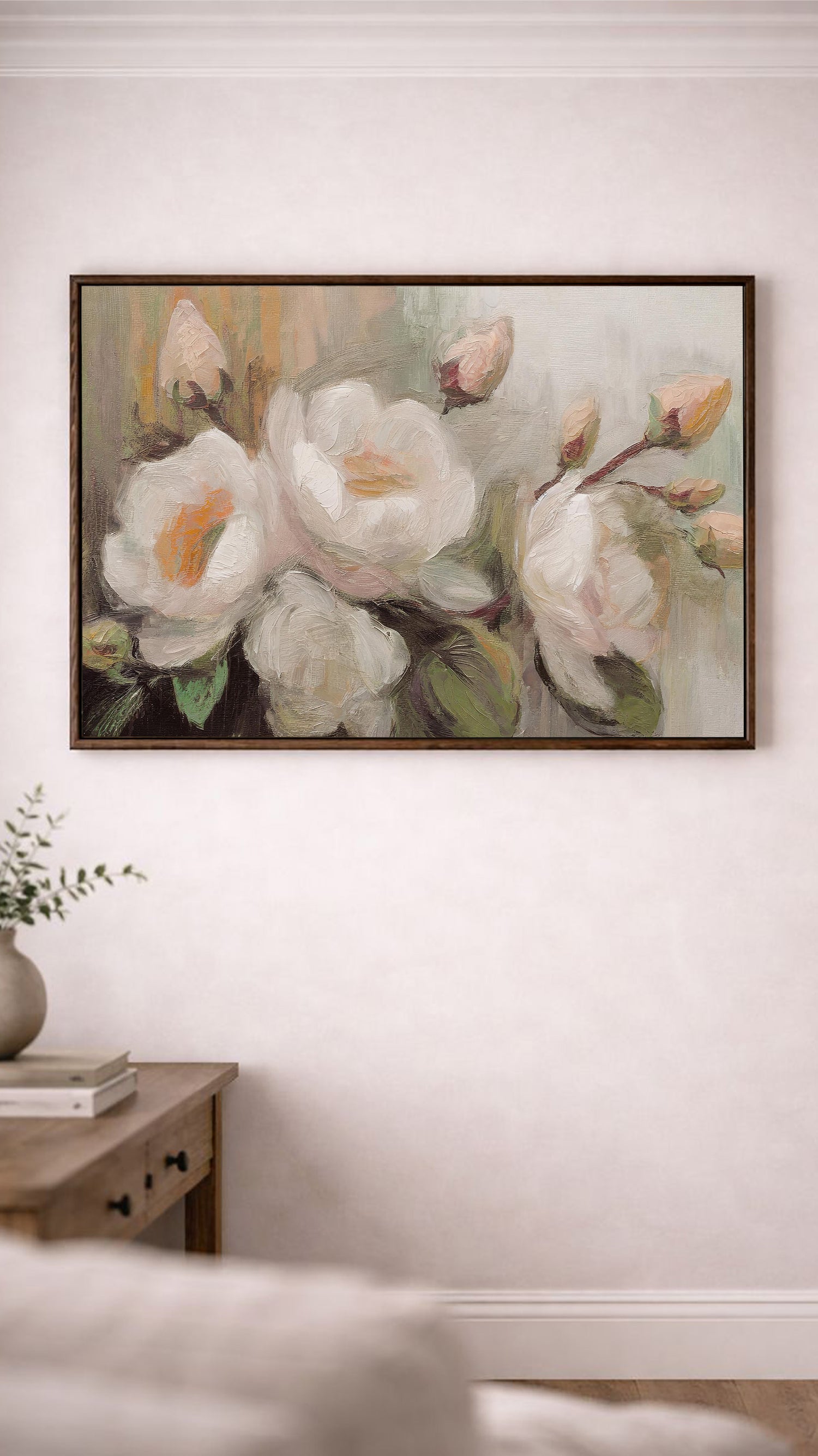 a large painting of white flowers hanging on a wall above a wooden table.