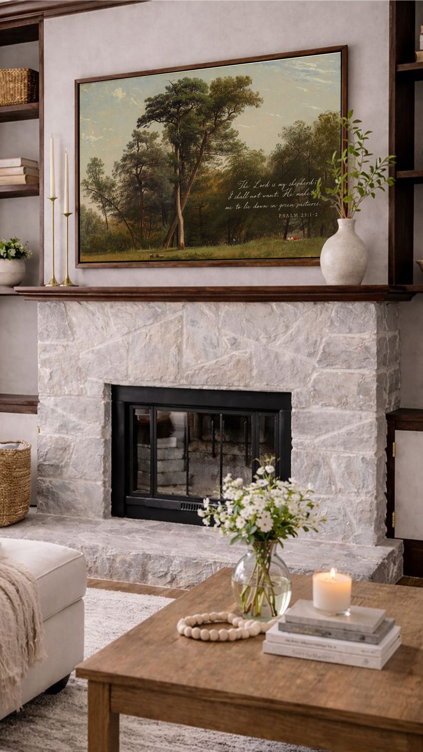 a cozy living room with a fireplace, a wooden coffee table, and a painting of a forest scene above it. The room is decorated with a vase of white flowers, a candle, and some books, creating a warm and inviting atmosphere.