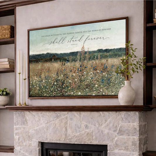 a cozy living room with a fireplace, a wooden coffee table, and a framed landscape painting above the fireplace. The painting depicts a field of flowers, and the room is decorated with a vase of flowers, a candle, and some books.