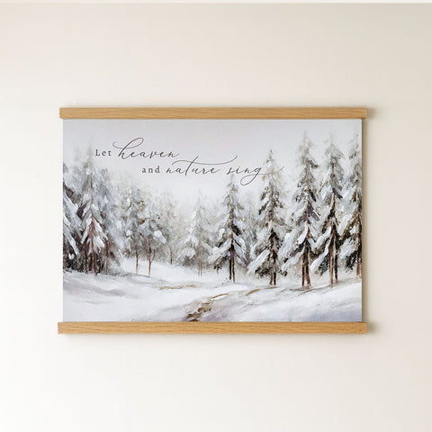 A framed painting depicting a snowy forest landscape with pine trees covered in snow.