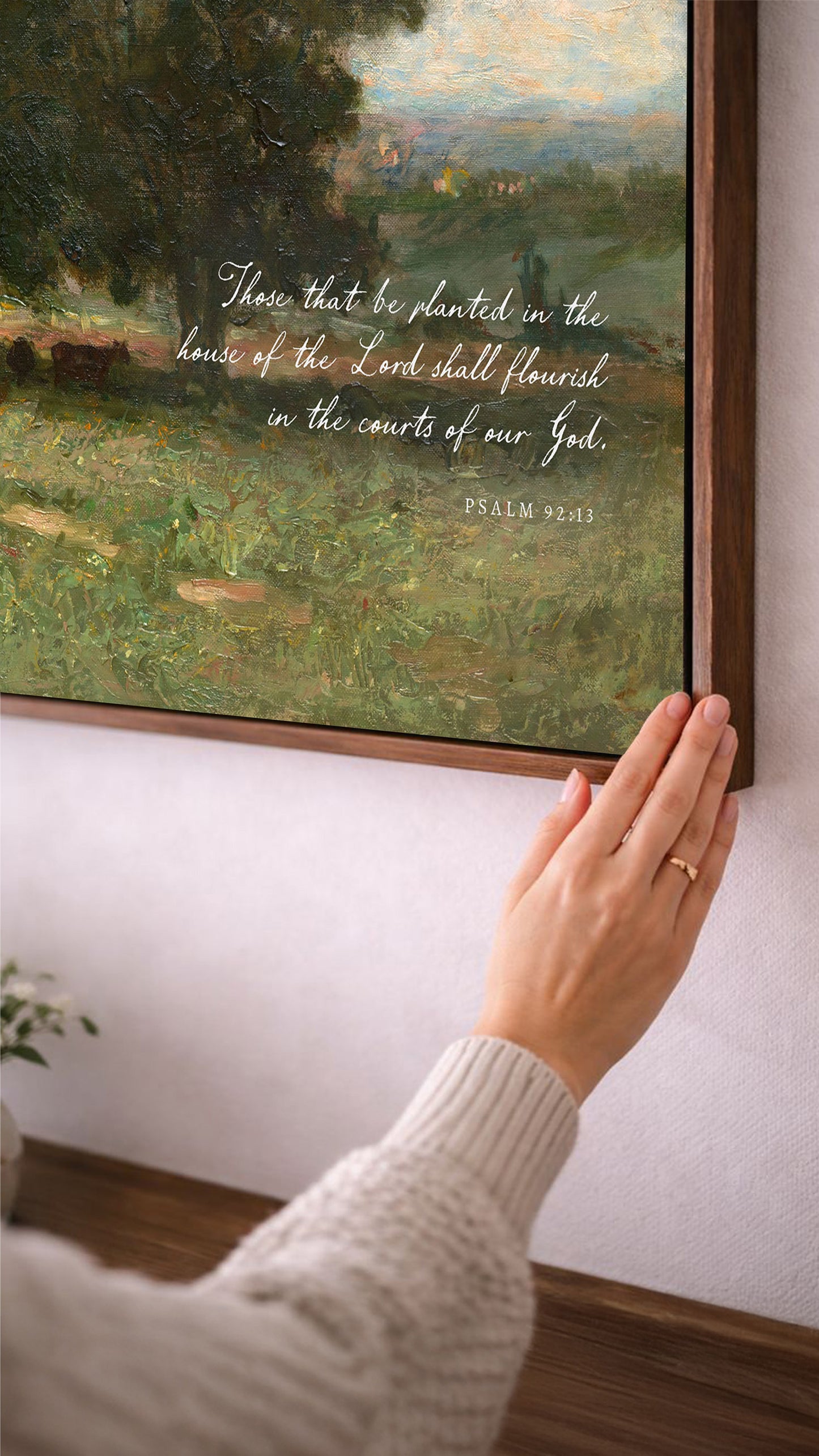 A person's hand is reaching towards a painting of a lush green landscape, with a text overlay that reads "There that be planted in the house of the Lord shall flourish in the courts of our God."