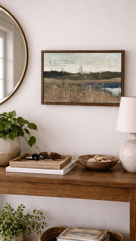 a wooden console table with various decorative items and a framed landscape painting hanging on the wall above it.