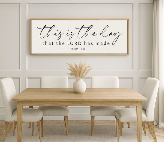 a dining room table with white chairs and a framed sign above it