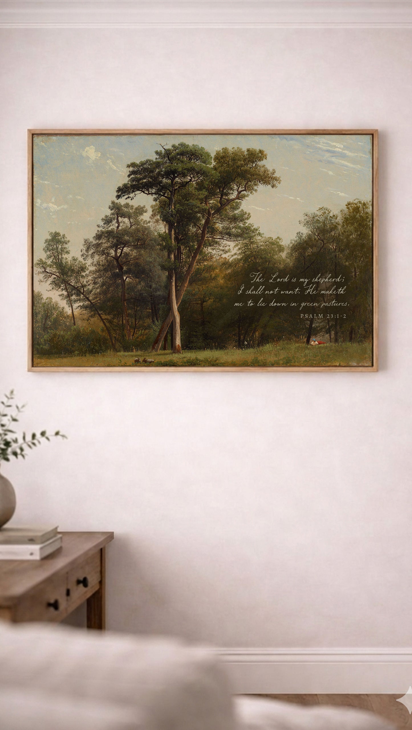 a painting of a serene landscape with a large tree in the foreground and a smaller tree in the background, set against a blue sky with clouds. The painting is hung on a white wall above a wooden table with a plant on it.