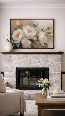 a cozy living room with a stone fireplace, a wooden coffee table, and a framed painting of white flowers above the fireplace.
