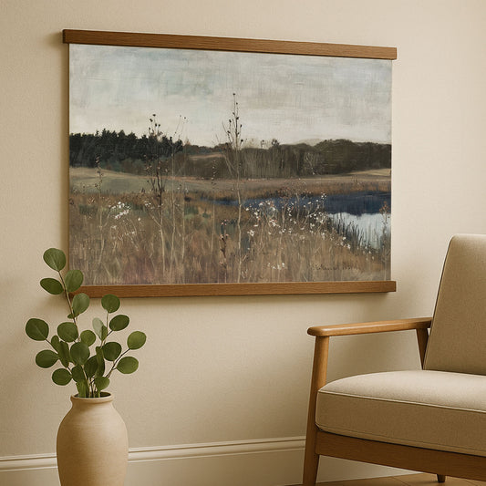 a large landscape painting hanging on a wall, with a wooden frame and a vase of greenery placed next to it.