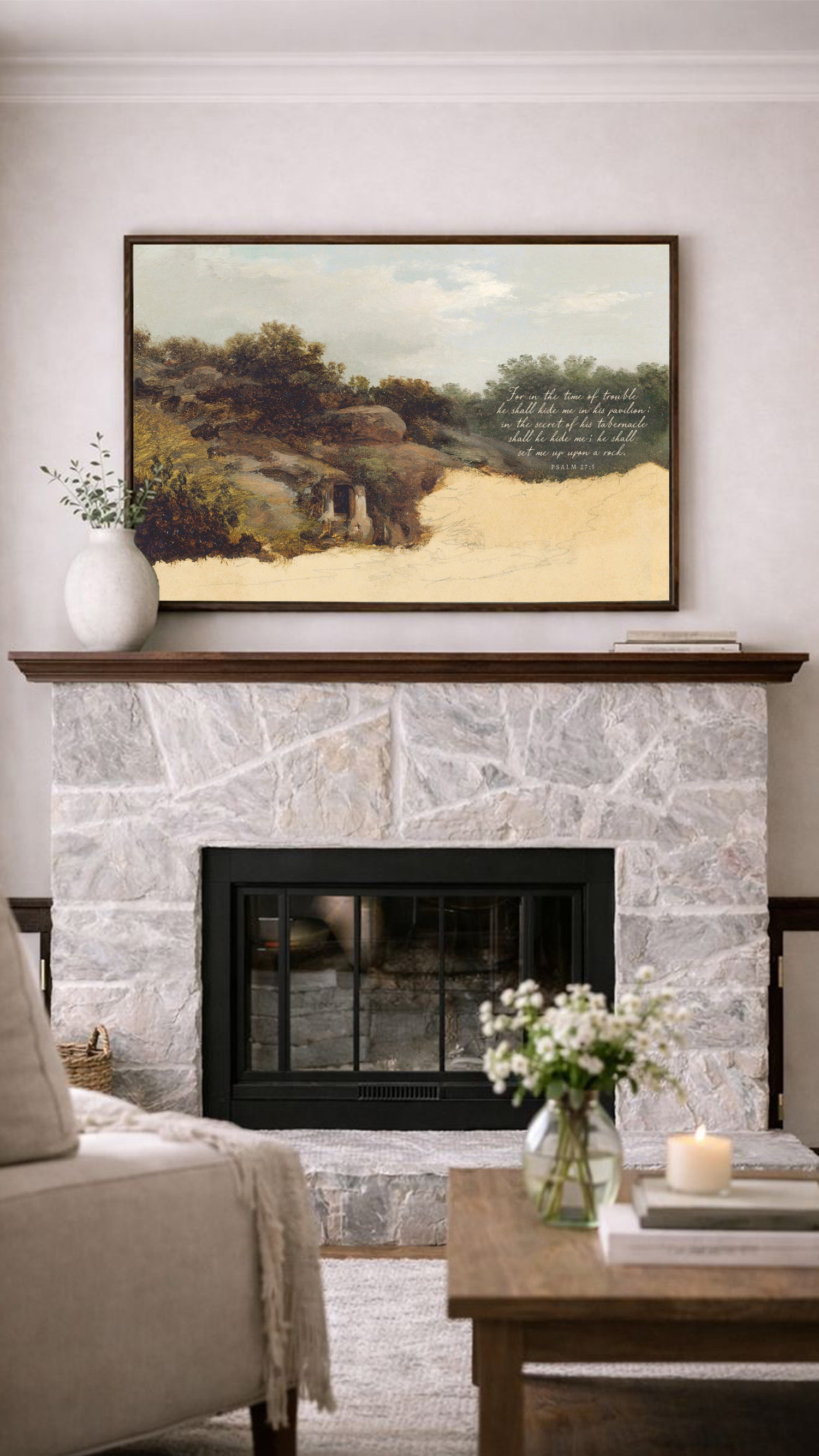 a cozy living room with a stone fireplace, a framed landscape painting above it, and a wooden coffee table with a vase of flowers in the foreground.
