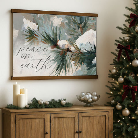 a wooden cabinet with a framed painting of pine branches and greenery hanging above it, along with a bowl of silver ornaments and candles on the cabinet.