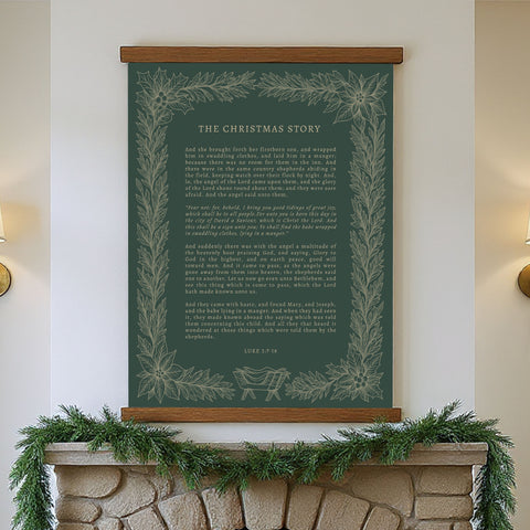 a framed Christmas-themed poster hanging on a wall above a fireplace, with a garland draped over the mantel.