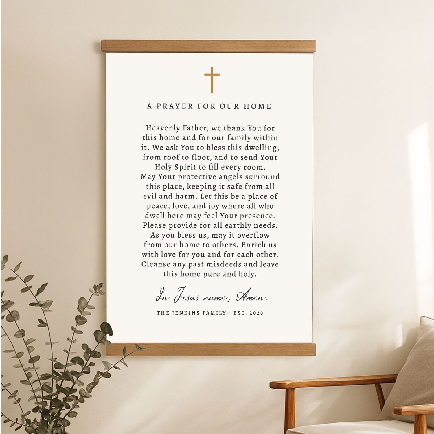 A prayer for our home poster with a cross and greenery on a wall.