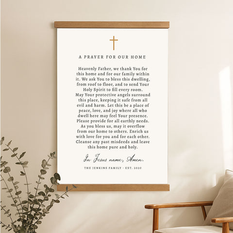 A prayer for our home poster with a cross and greenery on a wall.