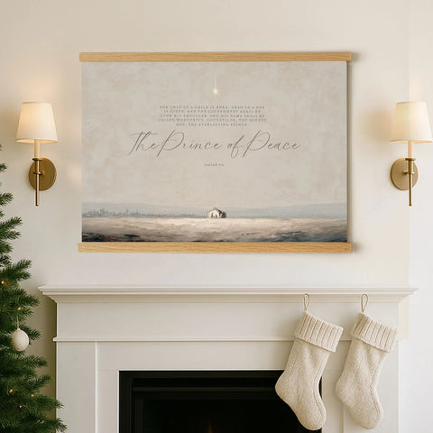 a fireplace with a framed painting of a serene landscape hanging above it, and two white stockings hanging from the mantle below.