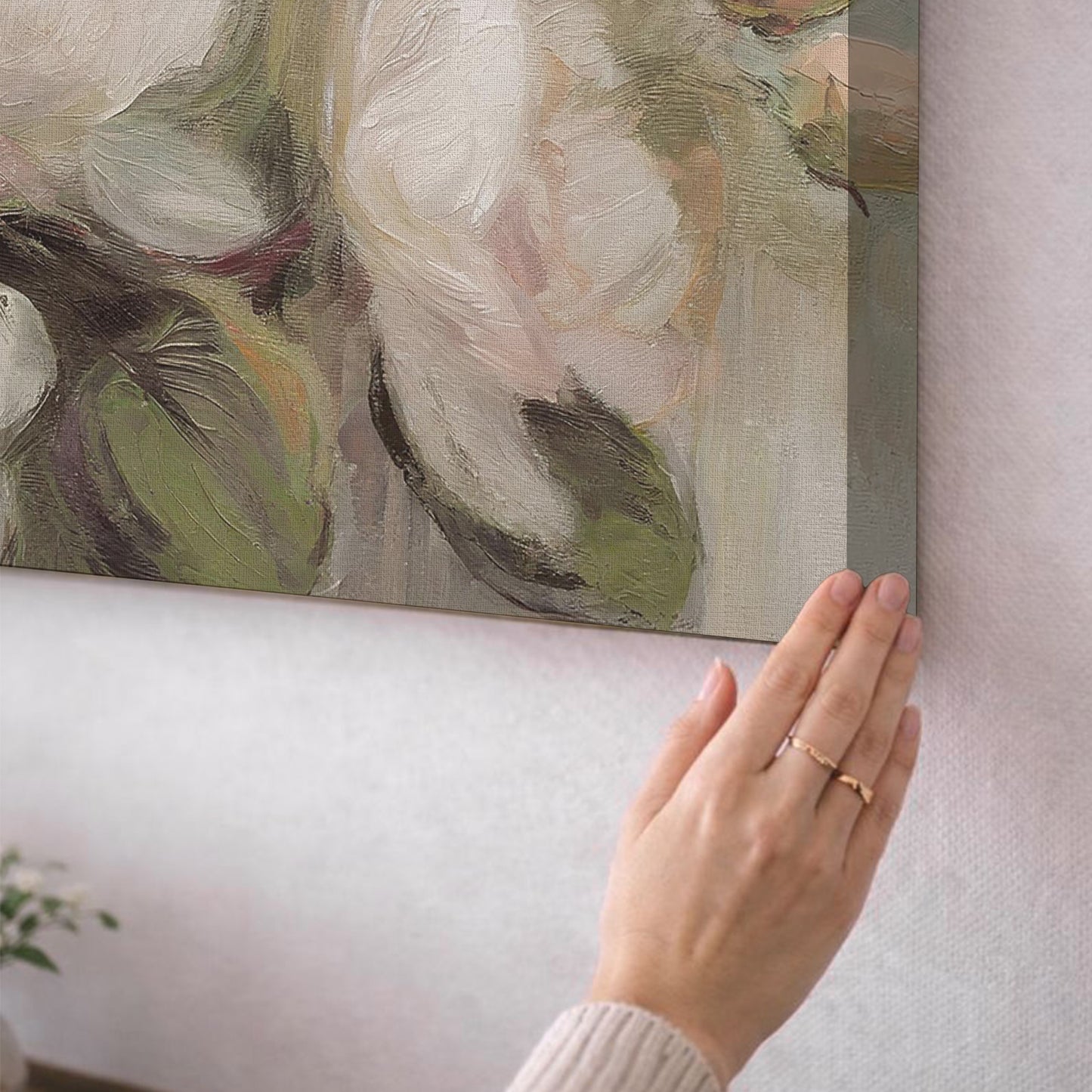 A person's hand is holding a painting, which appears to be a large abstract painting with a mix of green and white colors.