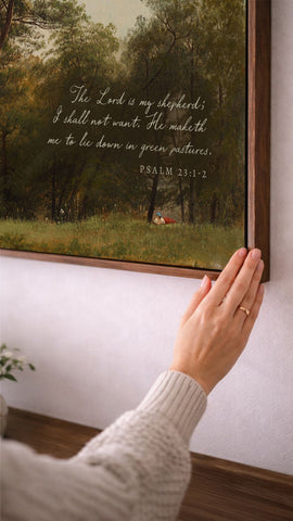 A person's hand is reaching towards a framed painting of a pastoral scene, with a text overlay that reads 