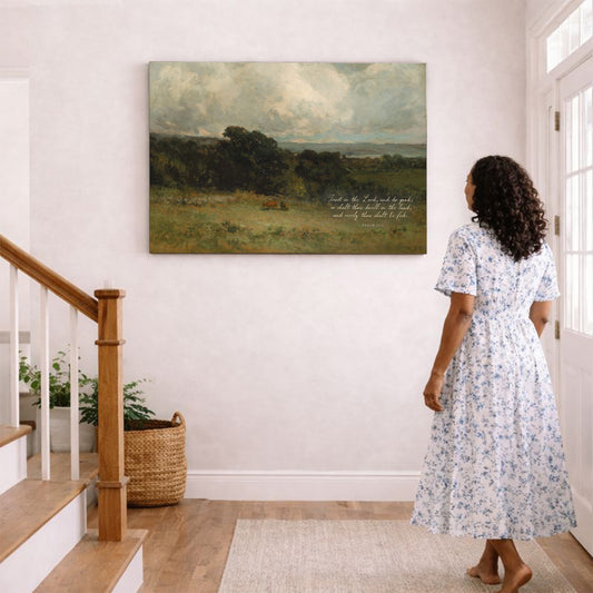 A woman in a white floral dress stands in a hallway, gazing at a large landscape painting on the wall.