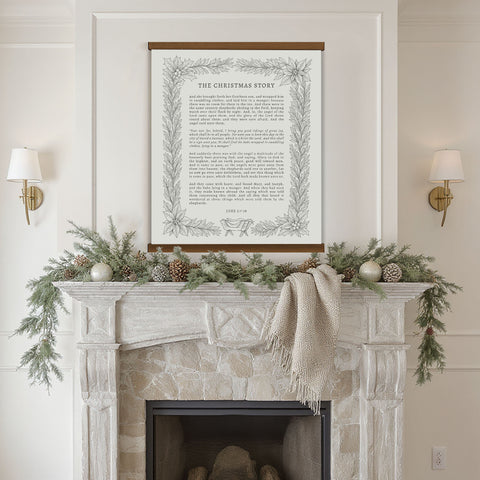 a fireplace mantel decorated with greenery, pine cones, and ornaments, with a framed text titled 