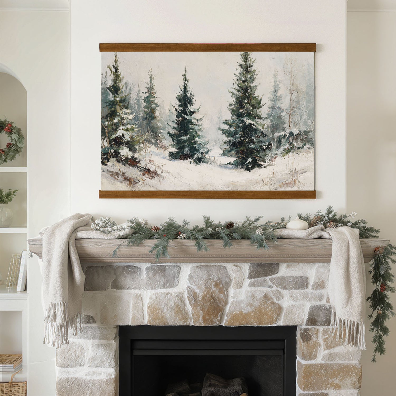 a cozy fireplace adorned with a wreath and greenery, with a framed painting of a snowy forest hanging above it.
