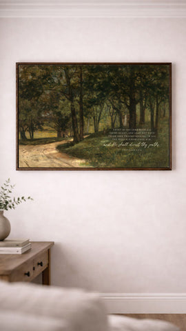 a painting of a forest scene hanging on a white wall, with a quote from the Bible below it.